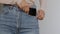 Close up shot of unrecognizable slim woman putting her smartphone into pocket of jeans, slow motion, empty space
