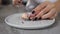 Close up shot of woman hands cutting macaroon on the halves using knife.