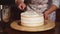 Close up shot of the woman`s hands, who spreads cream on the top of the dessert