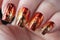 A close-up shot of a womans hand adorned with a stunning red and gold manicure, showcasing intricate and elegant nail