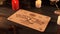 Close up shot of a wooden ouija board with a planchette on a table surrounded by candles, candlesticks and other