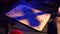 Close up shot of a wooden ouija board with a planchette on a table surrounded by candles, candlesticks and other