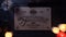 Close up shot of a wooden ouija board with a planchette on a table surrounded by candles, candlesticks and other