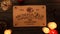 Close up shot of a wooden ouija board with a planchette on a table surrounded by candles, candlesticks and other