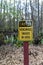 Close-up shot of a yellow and black sign against a backdrop of lush green trees in a forest setting