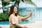 A close-up shot of a young Asian tourist taking a selfie with her cell phone happily at the poolside of her hotel on a weekend