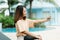 A close-up shot of a young Asian tourist taking a selfie with her cell phone happily at the poolside of her hotel on a weekend