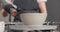 Close-up shot of young caucasian female potter in pottery workshop. Woman in apron is drying ceramic blank on rotating