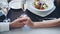 Close-up shot of young lovers touching and holding hands in classy restaurant. Table with sparkling champagne glasses