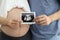 Close up shot of young pregnant belly wife and husband hands holding ultrasound film