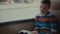 Close-up shot of a young schoolboy traveling by bus through city and reads a book.