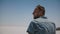 Close-up shot of young tired man in casual clothes lost, looking around in the middle of hot dry salt lake desert Utah.