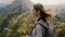 Close-up shot of young tourist woman with backpack and camera enjoying wind in her hair at amazing mountain scenery.