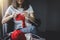 Close up shot of young woman hands knitting a red scarf handicraft in the living room on terrace at home