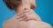 Close up shot of young woman massaging her neck, applying treatment cream to sore muscles, back view