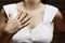 Close-up shot of a young woman in a white tank top with one hand on her chest.