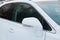 Close-up of the side left mirror and window of the car body white SUV on the street parking after washing and detailing in auto