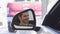 Close up of a side mirror of a car, happy male driver smiling