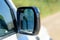 Close-up of the side right mirror and window of the car body white SUV. Exterior part of modern car. Road safety while