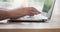 Close-up side view of a black lady typing on a laptop keyboard while working