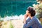 Close up Side view dreamy woman sitting on lakeside and enjoying beautiful serene day looking at lake and forest. Idyllic calm