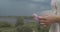 Close up side view of female hands holding wild flower trembling on wind on defocused background. Faceless woman