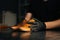 Close-up side view of hands of shoemaker shoemaker in black gloves holding old worn light brown leather shoes