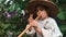 Close up side view of happy funny cute little boy in straw hat trying and learning to play on wooden flute, close up view