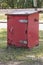 A Close up side view of a red old rusted post offcie post box storage unit
