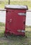 A Close up side view of a red old rusted post offcie post box storage unit