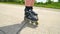 Close up side view to inline skating leg. Man easy riding on smooth way in forest park. Close up view to quick movement of inline