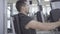 Close-up side view of young concentrated man exercising on gym equipment. Portrait of strong Caucasian sportsman using
