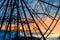 Close up silhouette of a part of ferris wheel without cabins on the blue and orange cloudy sky backgorund against the