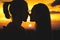 Close-up of the silhouettes of a young millenial couple in love getting ready to kiss with a man and girl against the