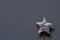 Close-up silver glitter plastic star with spring on gray background, minimalistic concept or background