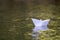 Close-up of simple small white origami paper boat floating quiet