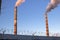 Close-up of a single concrete smoke stack rising into the dark blue sky with smoke billowing