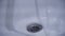 Close-up of sink drain with water. Cleaned metal sink drain glitters like new. Bathroom cleaning products that make them