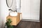 Close up of sink with oval mirror standing in on white wall , wooden cabinet with black faucet in minimalist bathroom. Side view.