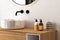Close up of sink with oval mirror standing in on white wall , wooden cabinet with black faucet in minimalist bathroom. Side view.