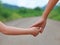 Close up of Sister hold hands with small children walking on the road