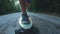 Close-up skateboarder boy riding outdoor. A young man rides a longboard on the highway. Misty road in the forest