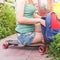 Close-up of skateboarder girl sitting on skateboard outdoor