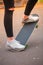 Close-up of a skateboarder`s foot in black sneakers.