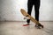 Close up of skateboarder standing next to a white brick wall. Athletic teenager wearing jeans with a skateboard. Urban style,