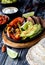 Close up of a skillet of a fajita mixture surrounded by fixings to make fajitas.