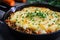 Close-up of a skillet filled with bubbling hot Shepherd\\\'s Pie, with a layer of mashed potatoes on top