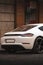Close-up sleek, white Porsche sports car is parked on a  city street