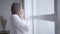 Close-up of sleepy young caucasian woman yawning and looking out the window in the morning. Side view of pretty brunette