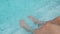 Close up of slender female legs against the clear blue water by the pool relaxing vacation on hot summer day under the sun.legs in